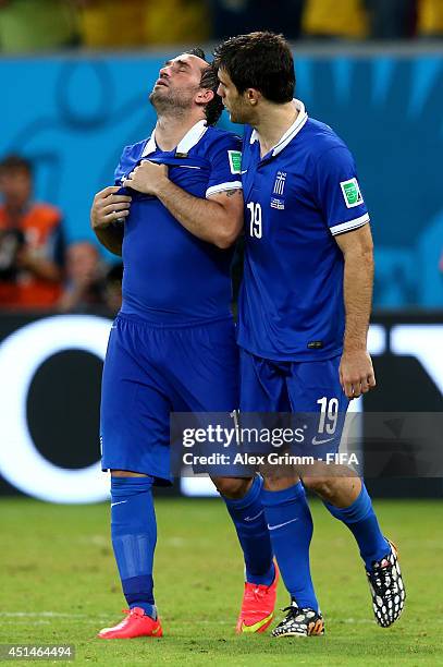 Theofanis Gekas of Greece walks off the pitch with Sokratis Papastathopoulos after the defeat in the 2014 FIFA World Cup Brazil Round of 16 match...