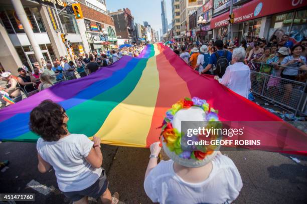 Participants in the WorldPride Parade march with a giant rainbow flag as the procession makes it way down Yonge Street in Toronto, Ontario, Canada,...