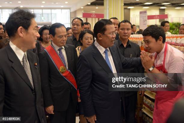 Cambodian Prime Minister Hun Sen speaks to an employee of AEON Mall as Japanese Foreign Minister Fumio Kishida and Motoya Okada , chief executive...