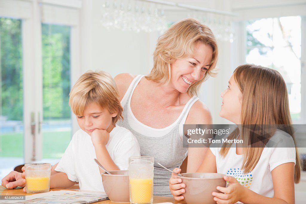 Femme et deux enfants dans la cuisine manger du petit déjeuner