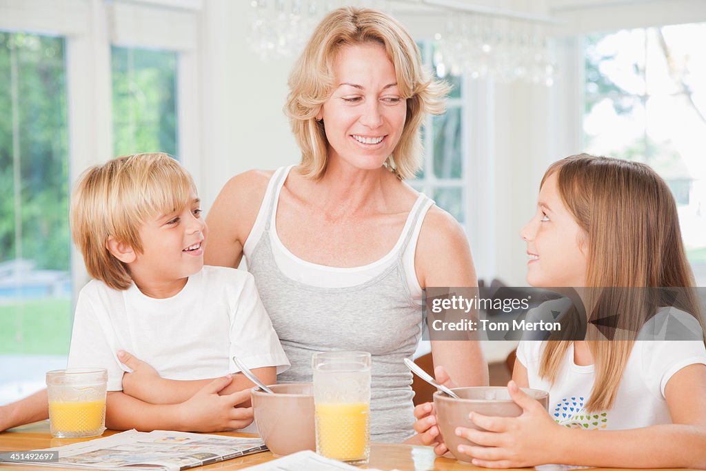 Woman and two kids in kitchen eating breakfast