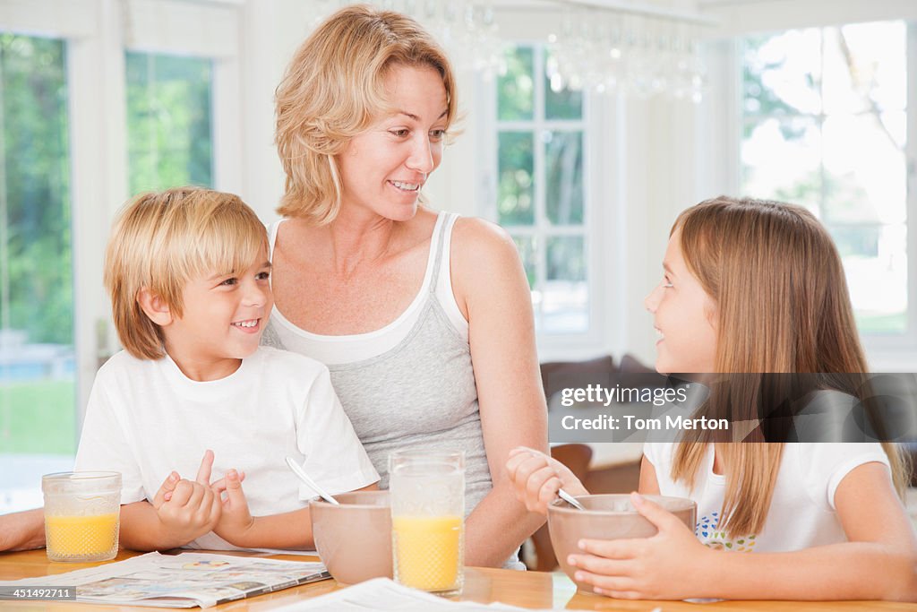 Woman and two kids in kitchen eating breakfast