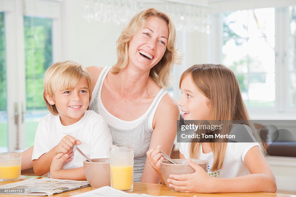 Woman and two kids in kitchen eating breakfast