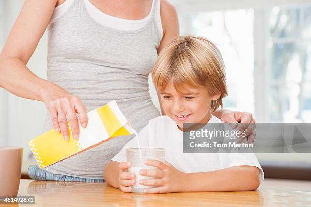 mulher na cozinha verter jovem rapaz copo de leite - mother son milk imagens e fotografias de stock