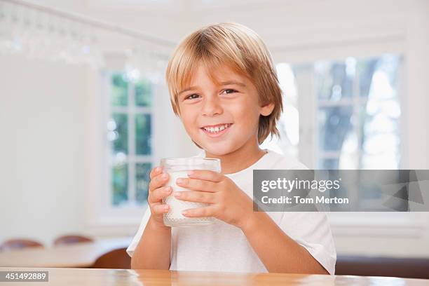 young boy in kitchen holding glass of milk - boy drinking milk stock pictures, royalty-free photos & images