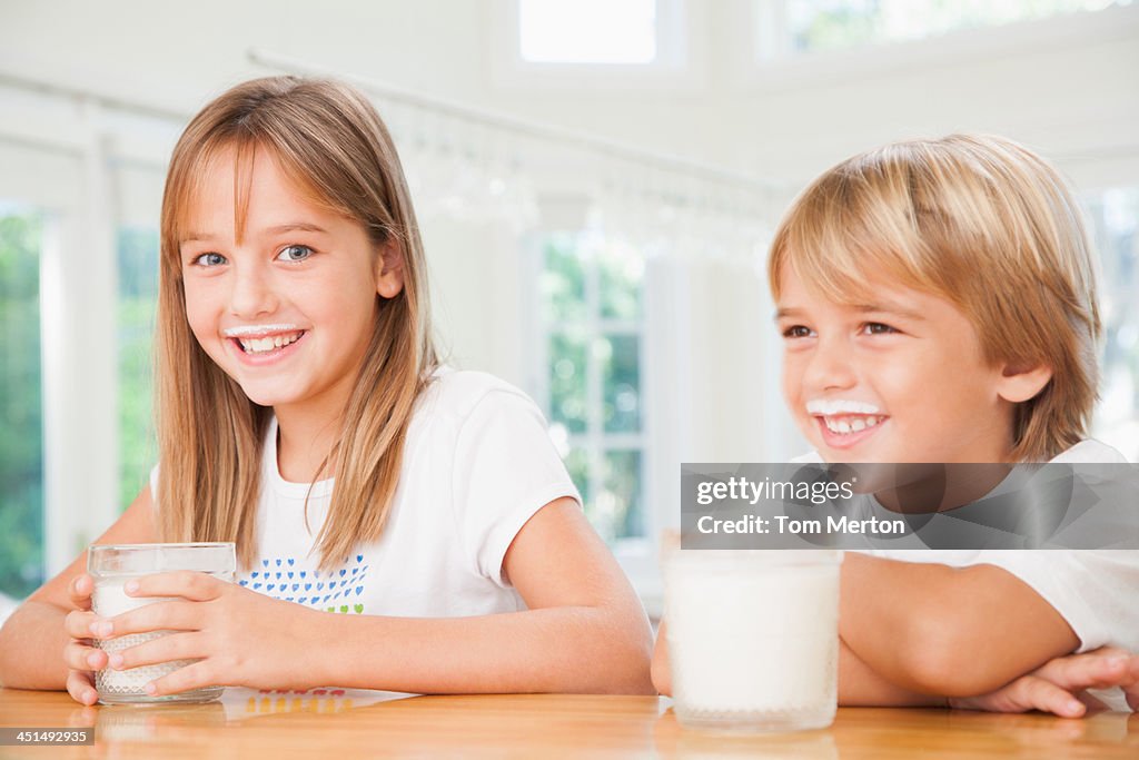 Young boy and young girl in kitchen with glasses of milk