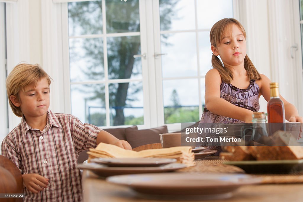 Young girl and boy in dining room setting table