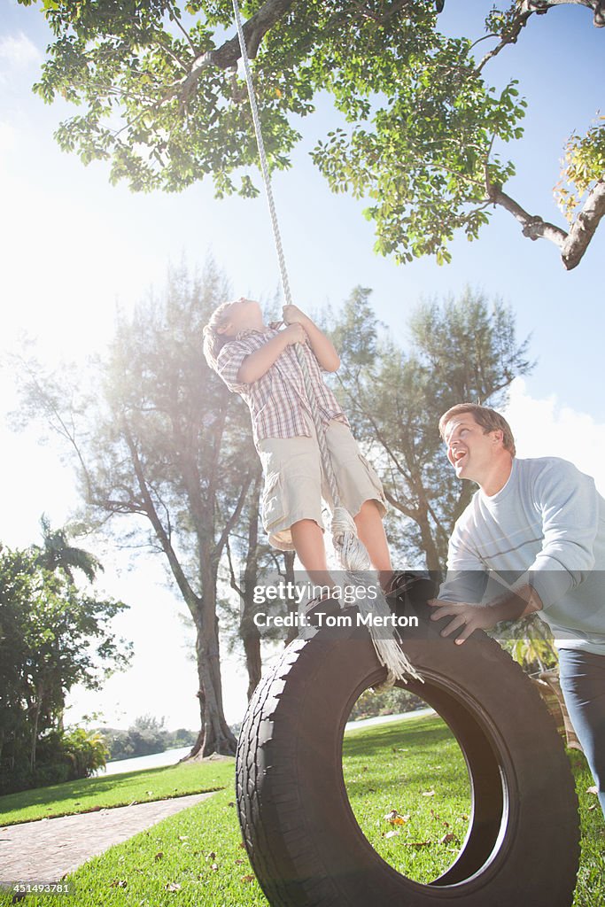 Man and young boy outdoors at park playing on tire swing