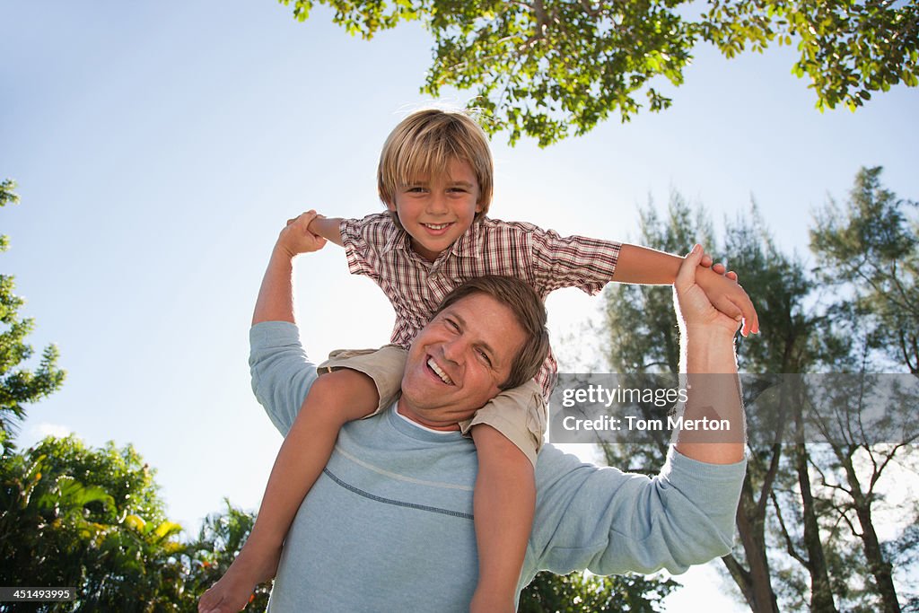 Man giving young boy shoulder ride outdoors at park