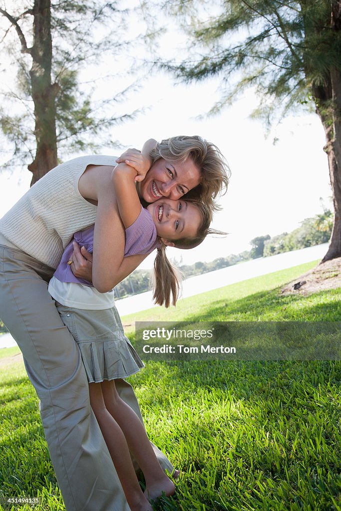 Woman and young girl playing outdoors at park by a lake