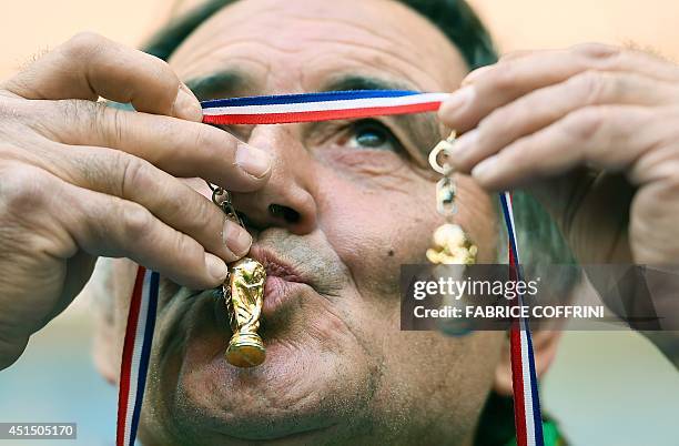 France fan kisses small mockups of the FIFA Football World Cup trophy prior to a Round of 16 football match between France and Nigeria at Mane...