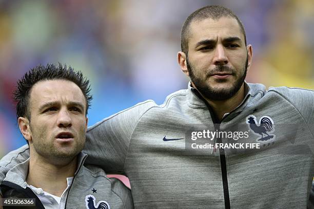 France's midfielder Mathieu Valbuena and forward Karim Benzema listen to their national anthem before the round of 16 football match between France...
