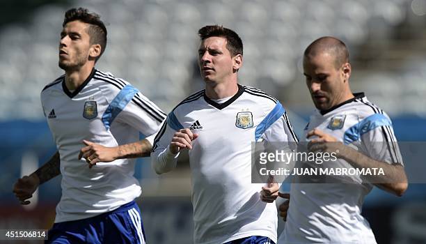 Argentina's forward Lionel Messi jogs next to midfielder Ricky Alvarez and forward Rodrigo Palacio during the official training session at The...