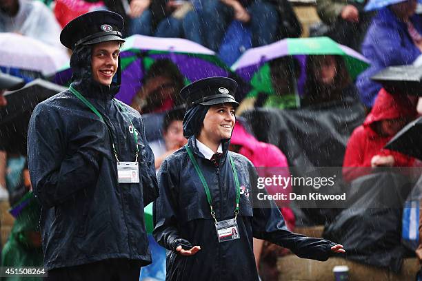 G4s Security out in the rain remain in good humor as fans sitting on Murray mound shelter under umbrellas as they watch the Andy Murray against Kevin...