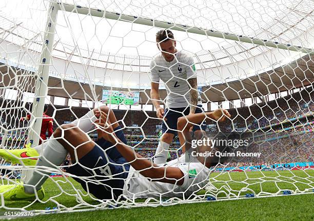 Raphael Varane of France lies in the next and is assisted by teammate Mathieu Debuchy during the 2014 FIFA World Cup Brazil Round of 16 match between...