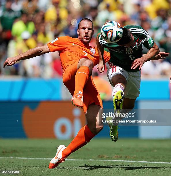 Ron Vlaar of the Netherlands and Hector Herrera of Mexico compete for the ball during the 2014 FIFA World Cup Brazil Round of 16 match between...
