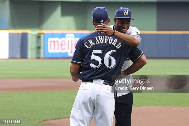 Jabari Parker of the Milwaukee Bucks hugs the Milwaukee Brewers assistant coach, Joe Crawford after he threw out the first pitch before the Milwaukee...