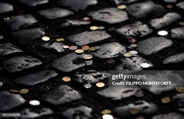 Coins usually thrown by tourists to make a wish are seen on the cobbles at the restoration site of the famous Trevi fountain on June 30, 2014 in...