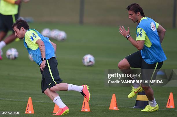 Brazil's forward Bernard and Brazil's defender Henrique warm up during a training session at the Granja Comary training complex in Teresopolis, on...