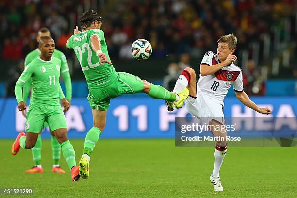 Mehdi Mostefa of Algeria and Toni Kroos of Germany compete for the ball during the 2014 FIFA World Cup Brazil Round of 16 match between Germany and...