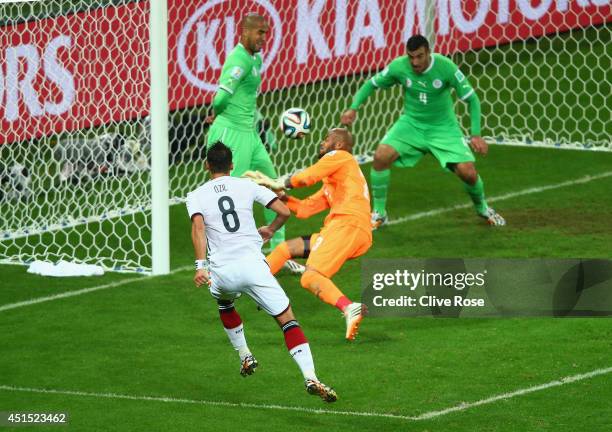 Mesut Oezil of Germany scores his team's second goal past Rais M'Bolhi of Algeria during the 2014 FIFA World Cup Brazil Round of 16 match between...