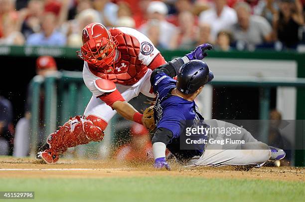 Troy Tulowitzki of the Colorado Rockies scores in the sixth inning ahead of the tag of Wilson Ramos of the Washington Nationals at Nationals Park on...