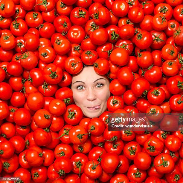 woman making funny face surrounded with tomatoes - funny vegetable stock pictures, royalty-free photos & images