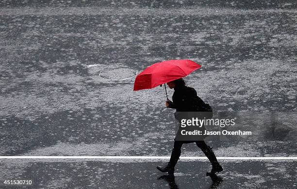 Pedestrian crosses in the intersection of Queen Street and Victoria Street during heavy rain on July 1, 2014 in Auckland, New Zealand. Heavy rain and...