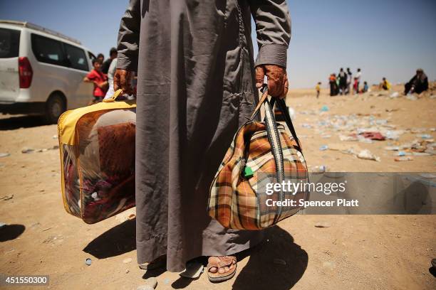 An elderly man holds his bags as over 1000 Iraqis who have fled fighting in and around the city of Mosul and Tal Afar wait at a Kurdish checkpoint in...