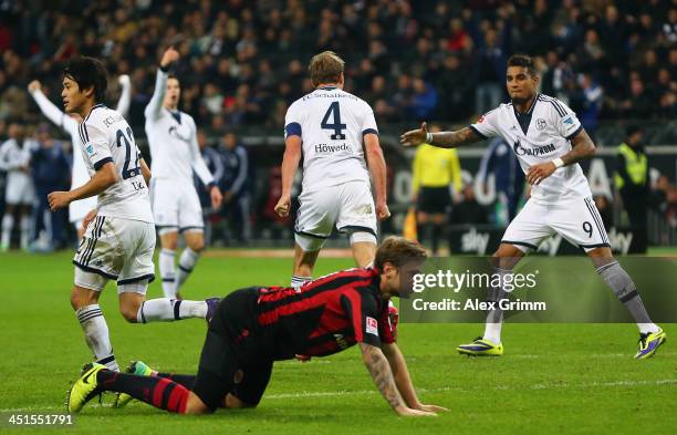 Marco Russ of Frankfurt reacts as Benedikt Hoewedes of Schalke celebrates his team's third goal with team mates during the Bundesliga match between...