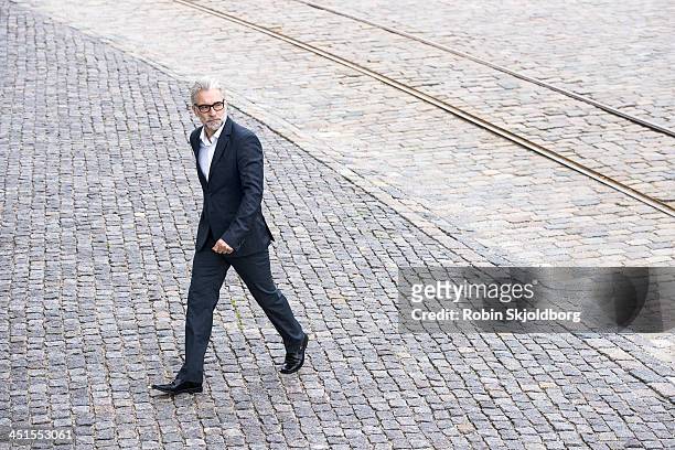 mature grey-haired man in suit walking - abbigliamento elegante foto e immagini stock