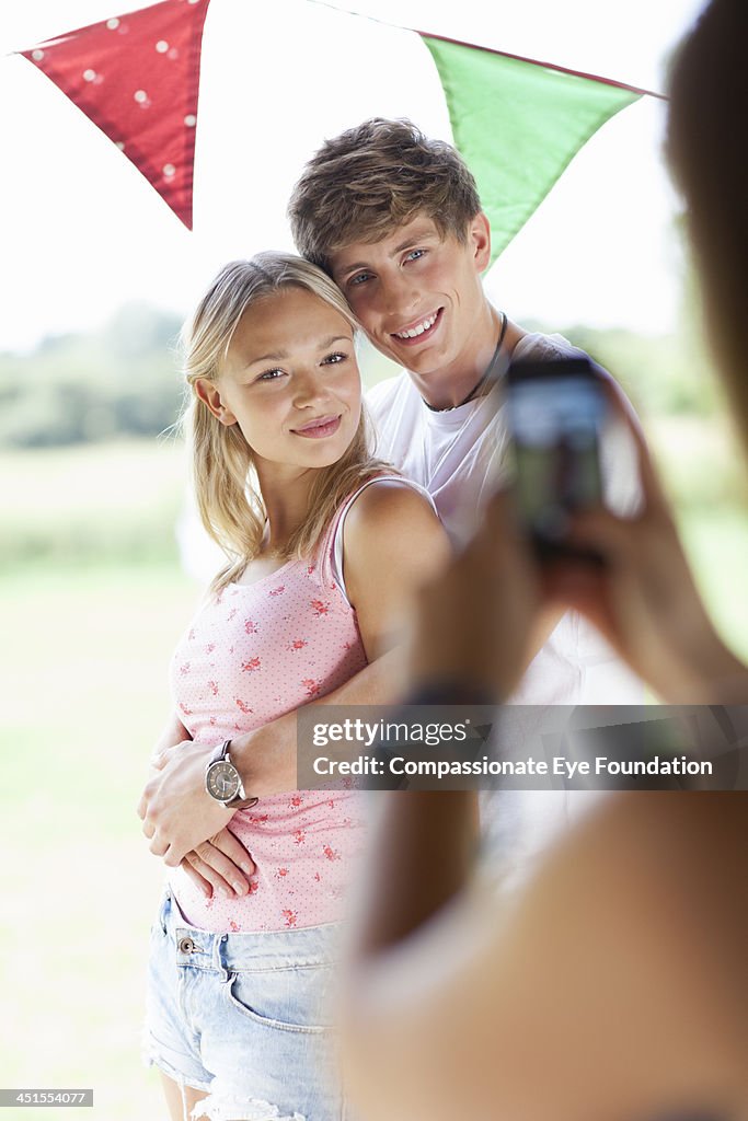 Woman taking picture of couple with smartphone