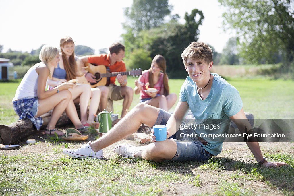 Group of friends with guitar relaxing by campfire