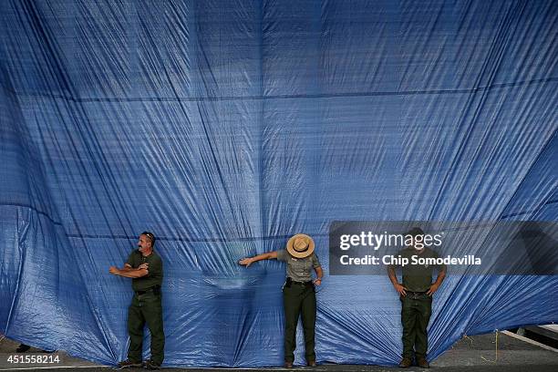 National Park Service employees work to keep the wind from blowing open a curtain of blue plastic tarps underneath the Whitehurst Freeway overpass...