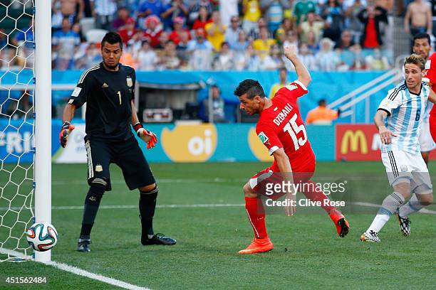 Blerim Dzemaili of Switzerland shoots the ball toward goal as Sergio Romero of Argentina looks on during the 2014 FIFA World Cup Brazil Round of 16...