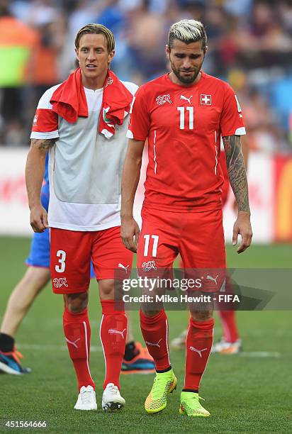 Reto Ziegler of Switzerland and Valon Behrami of Switzerland show their dejection as they walk off the pitch after the 0-1 defeat in the 2014 FIFA...