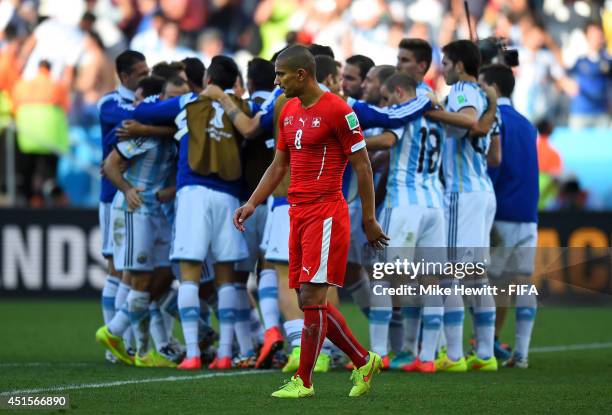 Gokhan Inler of Switzerland walks off the pitch while Argentina players celebrate after the 2014 FIFA World Cup Brazil Round of 16 match between...