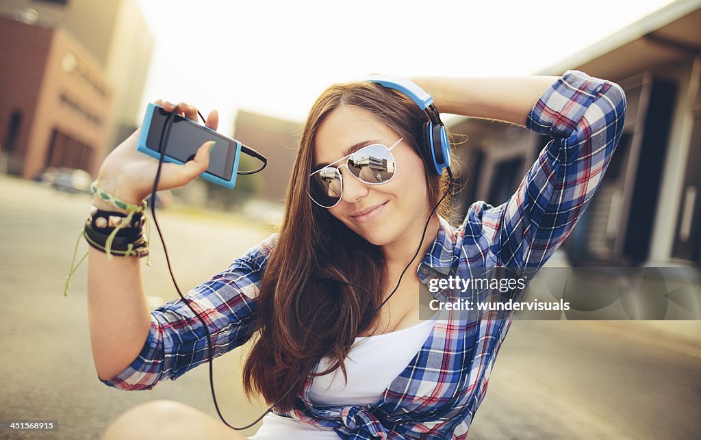 Dancing hipster girl with headphones in city during summer