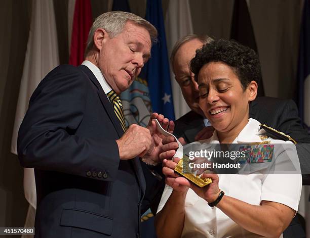 In this handout photo provided by the U.S. Navy, Adm. Michelle Howard lends a hand to Secretary of the Navy Ray Mabus as he and Wayne Cowles,...