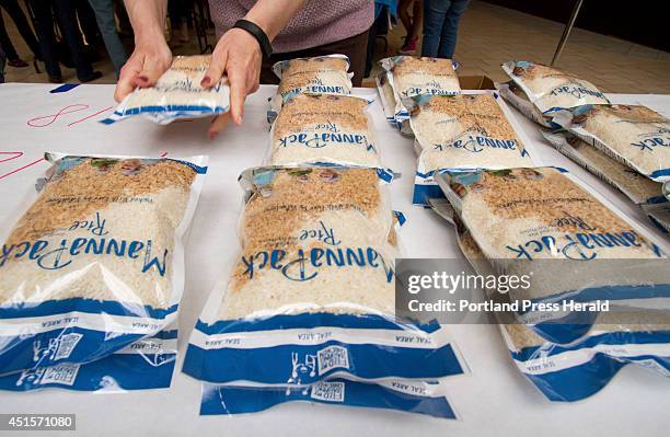 Volunteer stacks bags of rice and grains to feed hungry children around the world at the Maine Mall in South Portland on Sunday April 13, 2014. About...