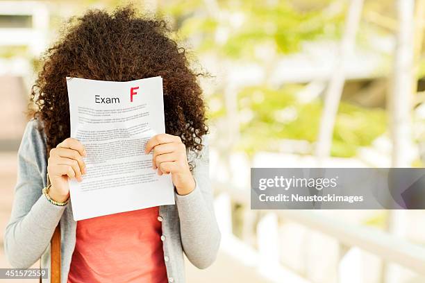 disappointed girl holding result in front of face on campus - miss f stock pictures, royalty-free photos & images