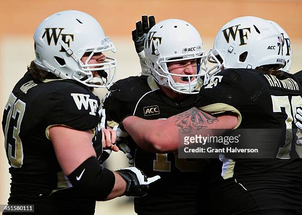Tanner Price celebrates with teammates Steven Chase and Tyler Hayworth of the Wake Forest Demon Deacons celebrate after Price's touchdown against the...