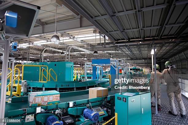 Parcels, including a Yamato Transport Co. Branded box, left, move along a conveyor before passing through a scanning machine as employees monitor...
