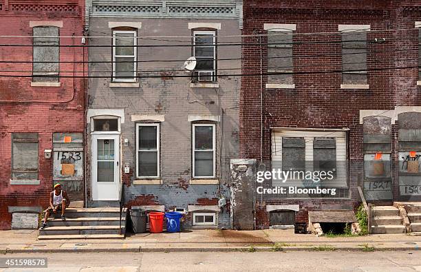 Man sits on stairs on the street in front of an abandoned home in Camden, New Jersey, U.S., on Monday, June 23, 2014. Artist Chris Toepfer, founder...