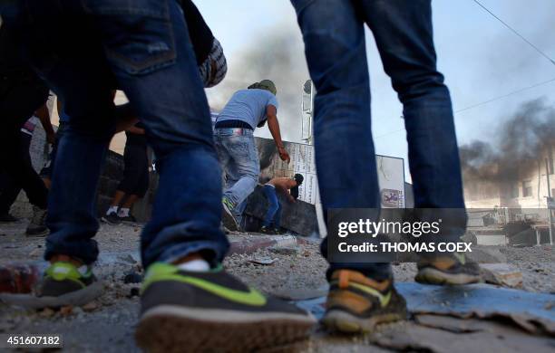 Masked Palestinian protesters throw stones toward Israeli police during clashes in the Shuafat neighborhood in Israeli-annexed Arab East Jerusalem,...