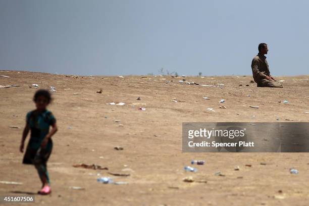 An Iraqi man prays near an entrance to a camp as thousands of Iraqis who have fled recent fighting in the cities of Mosul and Tal Afar try to enter a...