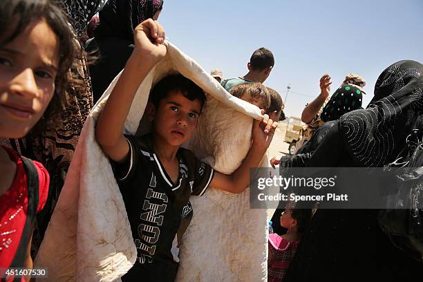 Iraqis who have fled recent fighting in the cities of Mosul and Tal Afar try to enter a temporary displacement camp but are blocked by Kurdish...