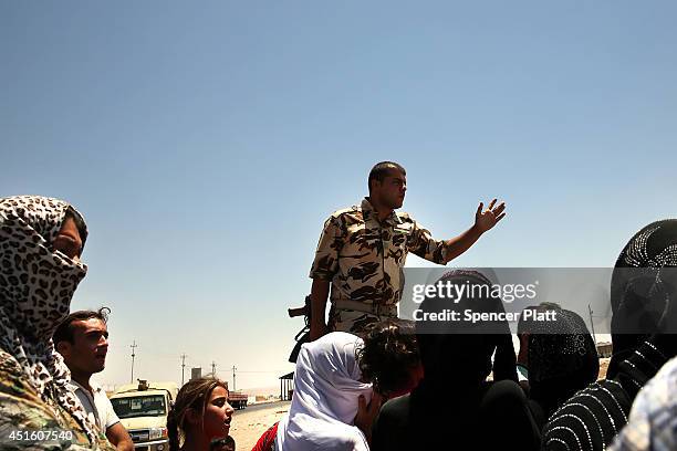 Iraqis who have fled recent fighting in the cities of Mosul and Tal Afar try to enter a temporary displacement camp but are blocked by Kurdish...