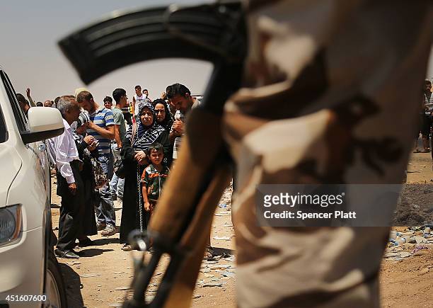 Iraqis who have fled recent fighting in the cities of Mosul and Tal Afar try to enter a temporary displacement camp but are blocked by Kurdish...