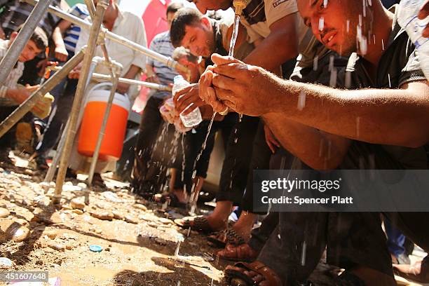 Displaced Iraqi's consume water from a temporary faucet as thousands of Iraqis who have fled recent fighting in the cities of Mosul and Tal Afar try...